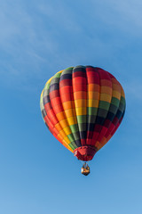 This is a photo of a beautiful hot air balloon slowly sailing through a calm blue sky.