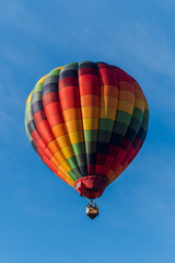 This is a photo of a beautiful hot air balloon slowly sailing through a calm blue sky.
