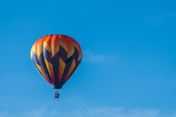 This is a photo of a beautiful hot air balloon slowly sailing through a calm blue sky.