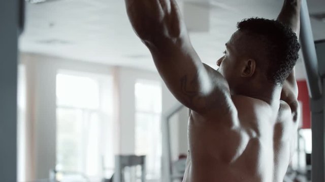 Athletic man pulling up on horizontal bar in fitness gym
