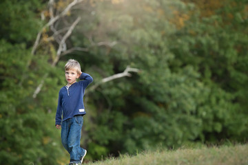 blonde boy walking alone and sad in the woods