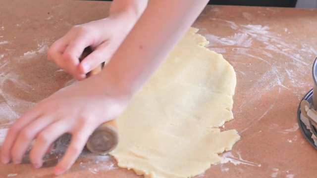 Baker kneading dough with rolling pin on table prepares bread or apple pie