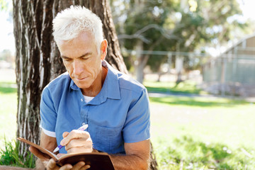 Senior man sittingin park while reading book
