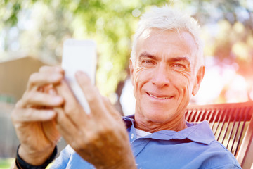 LoMature man outdoors using mobile phone