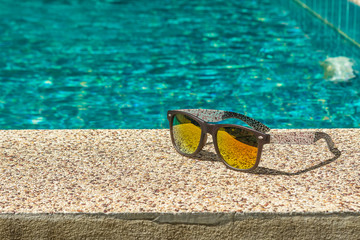 Cool sunglasses on the gravel poolside floor in sunny day.