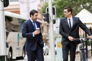 Two young businessmen with a bike in city centre