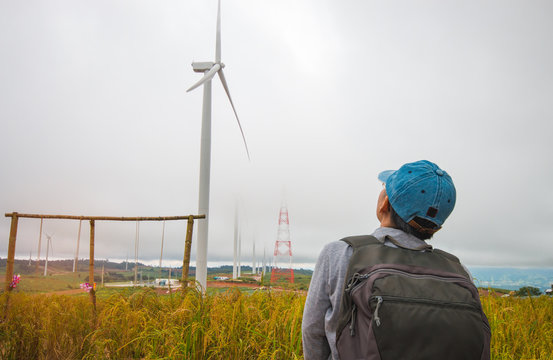 visitor backpage looking wind turbine in fog, at hill in thailan