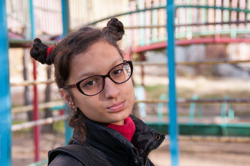 Portrait of a girl with glasses on the background of the playground