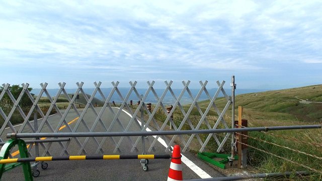 2016年4月の熊本地震から半年後の阿蘇山・米塚近辺の風景。　半年経っても、米塚前の道路は通行止め状態。　奥に小さく見えるのが米塚。