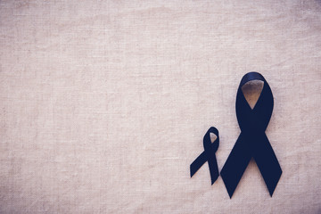 Black ribbons on linen copy space toning background, for Skin cancer awareness, Melanoma...
