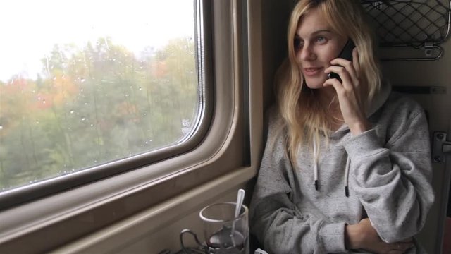 Girl Talking on the Phone Sitting in a Train Window