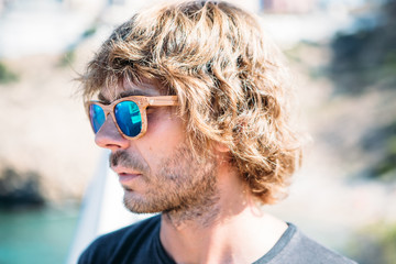 Long haired stylish man in wooden sunglasses