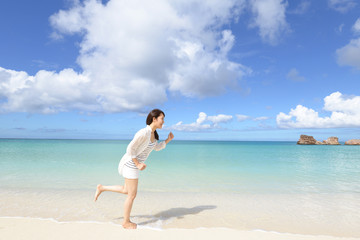 Fototapeta na wymiar 南国沖縄の美しいビーチで走る女性
