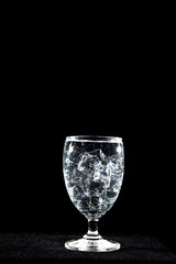 water with glass at black background