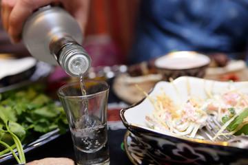 Person filling a glass of vodka