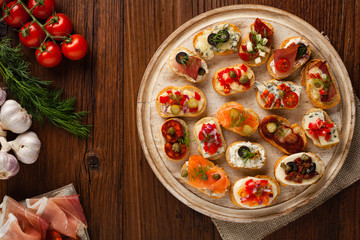 Crostini with different toppings on wooden background. Delicious appetizers. Top view.