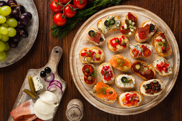 Crostini with different toppings on wooden background. Delicious appetizers. Top view.