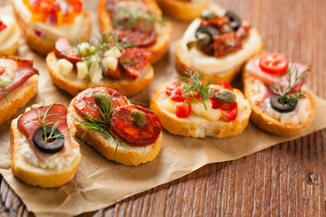 Crostini with different toppings on wooden background. Delicious appetizers. Front view.