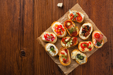 Crostini with different toppings on wooden background. Delicious appetizers. Top view.