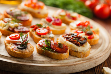 Crostini with different toppings on wooden background. Delicious appetizers. Front view.