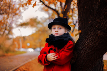 beautiful girl in a hat standing by the tree in the park autumn day