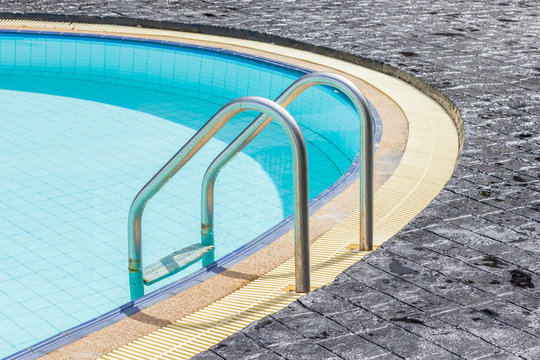 A view of a light clear blue swimming pool with steel ladder.
