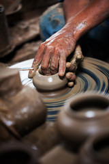 dirty hands making pottery in clay on wheel