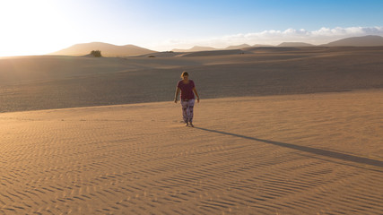 Fototapeta na wymiar woman walks alone in the desert at sunset