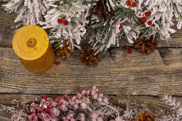 Fir branch and berries in snow, cone and candle on wooden background. Christmas theme. Template