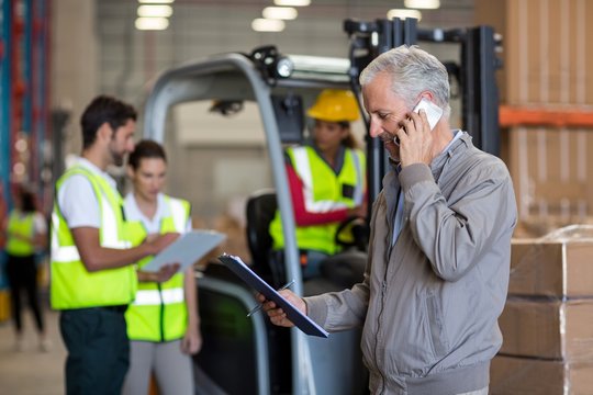 Warehouse manager talking on mobile phone 