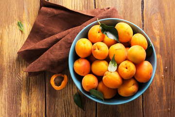 Ceramic bowl of fresh harvested apricots over wooden table