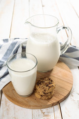 fresh milk in glass jug and glass on wooden background