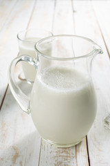 fresh milk in glass jug and glass on wooden background