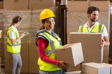 Portrait of warehouse worker carrying a cardboard box