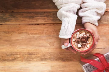 Crédence de cuisine en verre imprimé Chocolat main féminine tenant une tasse de chocolat chaud ou de chocolat avec de la guimauve sur une table en bois d& 39 en haut