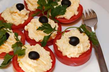 Decoration of stuffed tomatoes. Food vegetable on the plate. Tomatoes with cream and black olives. Cold snack lunch.