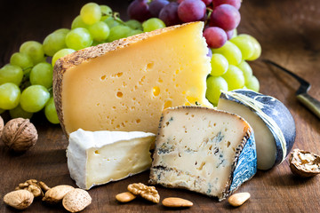 Appetizing cheese variety with nuts and grapes.