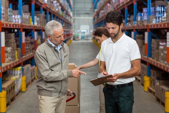 Warehouse manager and male worker interacting while working 