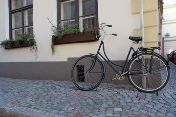 Fototapeta na wymiar Parked bicycle in narrow street in the old town of Riga, vintage style.