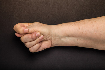 Hands of elderly woman on black background. Toned