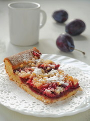 A piece of Bavarian plum pie on white plate with milk. Selective focus.