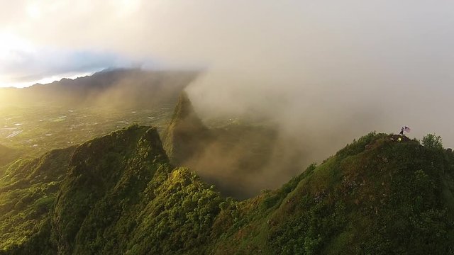 People with American flag at Mount Olomana in Kailua, Hawaii, aerial pan.