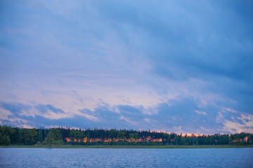 Sunset on the lake in red and blue colors with trees