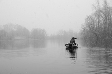 Man in boat on lake during winter snowy day