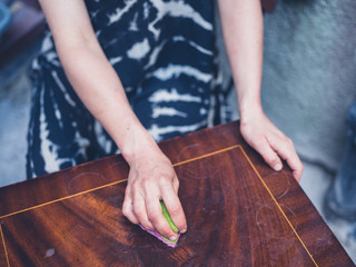 Young woman cleaning old furniture