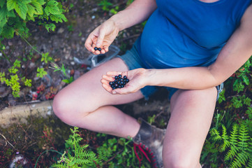 Pregnant woman with black currants in garden