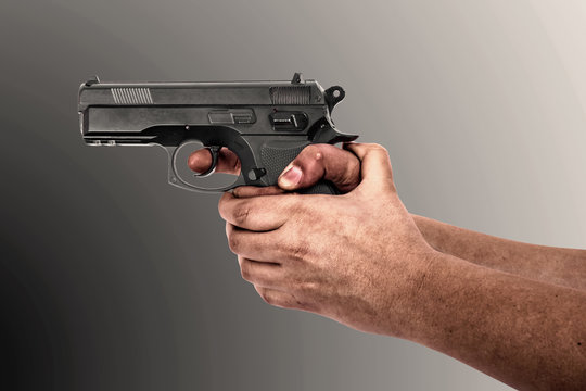 Hand holding a gun isolated on grey background
