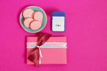 Macarons with ring on a pink background . An offer of marriage. Top view, toned image, film effect