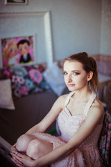 Girl in peach dress sits in the room with pink paintings