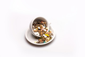 Medical capsules and tablets inside coffee cup